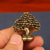 Brass fortune tree ornament featuring pinecone shapes and ingot accents held in a hand.