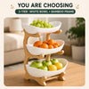 A wooden 3-tier fruit basket stand holding green grapes, oranges, and green apples.