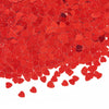 A pile of red heart-shaped foil confetti scattered across a white background.