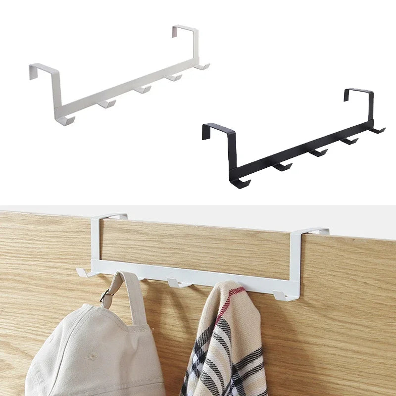 A black iron door and wall organizer rack with five hooks mounted on a light wood surface.