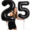 A young woman holds up giant black foil balloons shaped like the number 25.