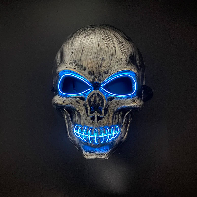 A realistic latex skull mask with glowing blue eyes and teeth against a dark background.
