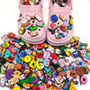 A pair of pink PVC shoe charms for clogs and slides, featuring various colorful and themed decorations.
