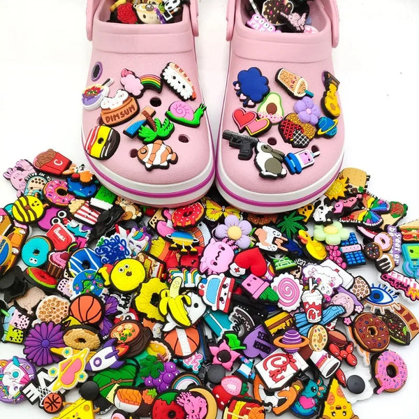 A pair of pink PVC shoe charms for clogs and slides, featuring various colorful and themed decorations.