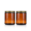 A set of two amber glass jars with airtight lids and labels sitting on a white background.