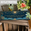 A rectangular blue tin sign with gold celestial designs and text on a wooden surface.