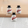 A set of festive Christmas resin decor featuring two white snowman figures with black hats and red scarves.