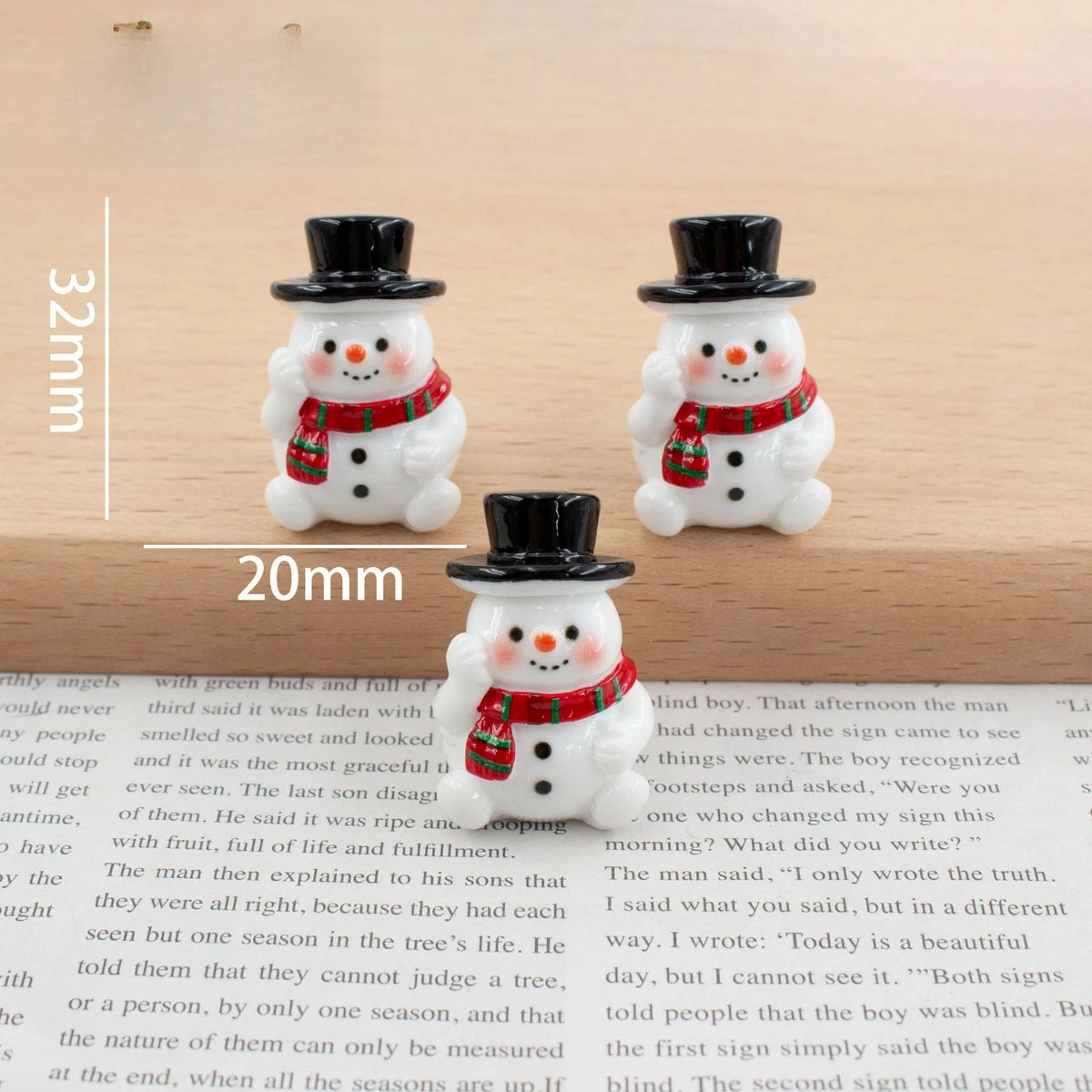 A set of festive Christmas resin decor featuring two white snowman figures with black hats and red scarves.