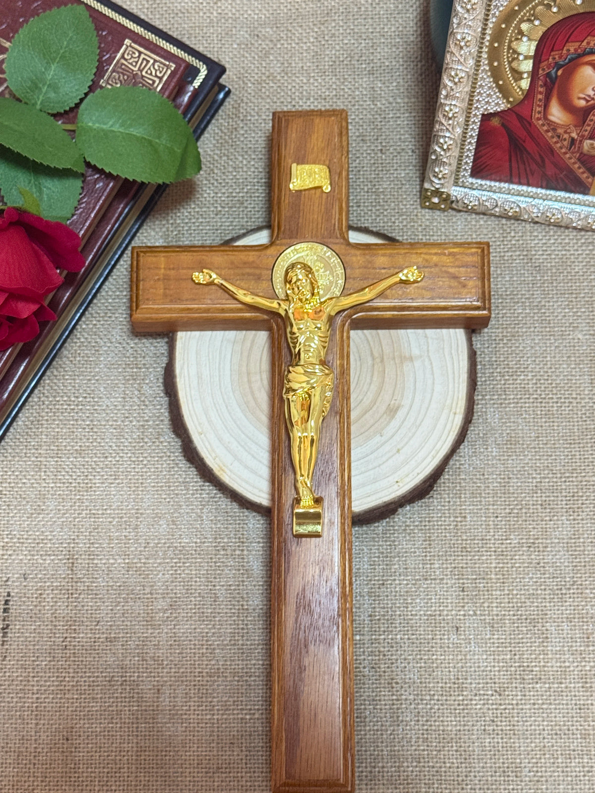 A wooden crucifix with a gold Jesus figure mounted on a cross, set against a beige fabric background.