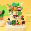 A tiered cake decorated with jungle animal toppers including a lion, monkey, elephant, and giraffe on a yellow background.