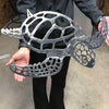 A person holds a silver metal sea turtle wall art sculpture against a neutral background.