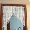 A sheer white beaded lace valance curtain hanging in a wooden frame.