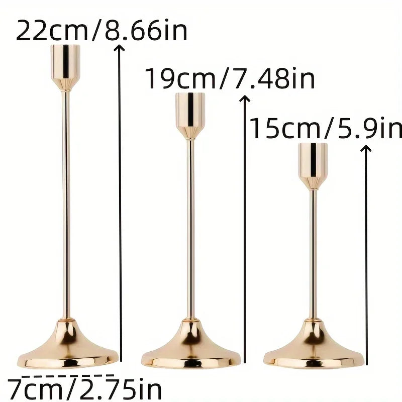 A set of three elegant gold-toned metal candle holders with varying heights and flared bases.