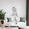 Elegant metal line art wall decor featuring a figure in a reclining pose on a white sofa.
