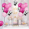 A display of pink and black cow print balloons for a farm-themed party decoration.