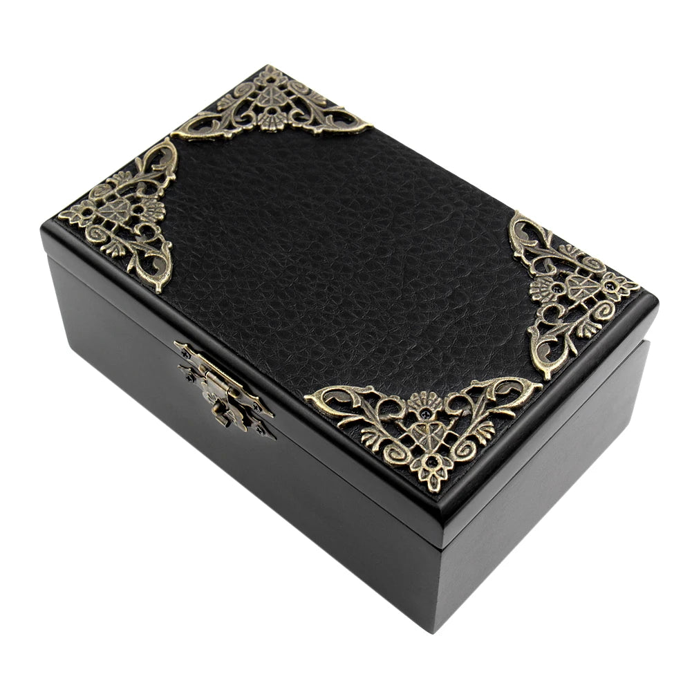 A black wooden music box with gold filigree decoration, shown from above.