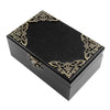A black wooden music box with gold filigree decoration, shown from above.