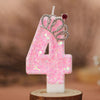 Pink glitter number four candle with a silver crown topper on a wooden base