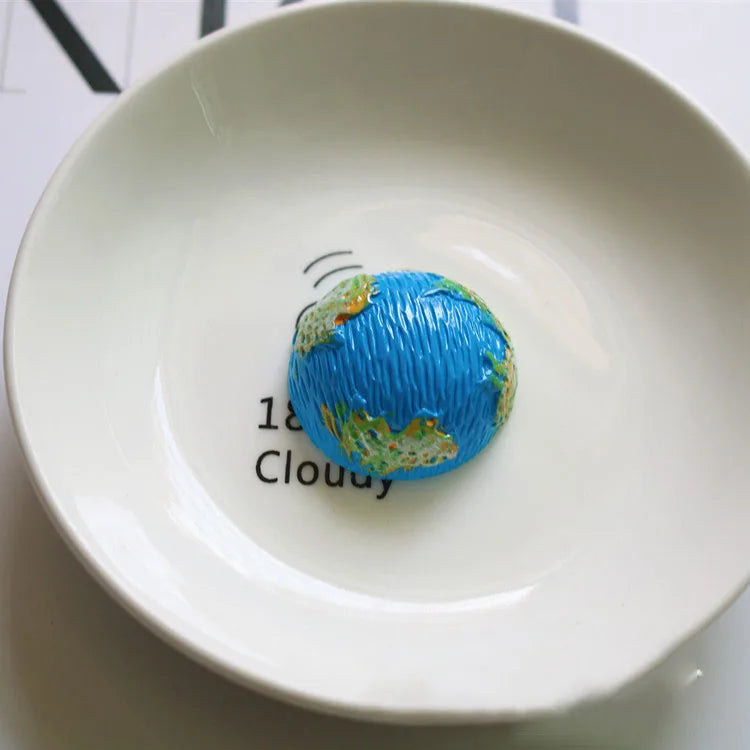 Une assiette blanche présente une petite décoration sphérique bleue avec un motif de nuage et du texte.