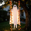 Decoración fantasma de tela blanca con detalles de hoja de arce colgando de una rama de árbol al aire libre.
