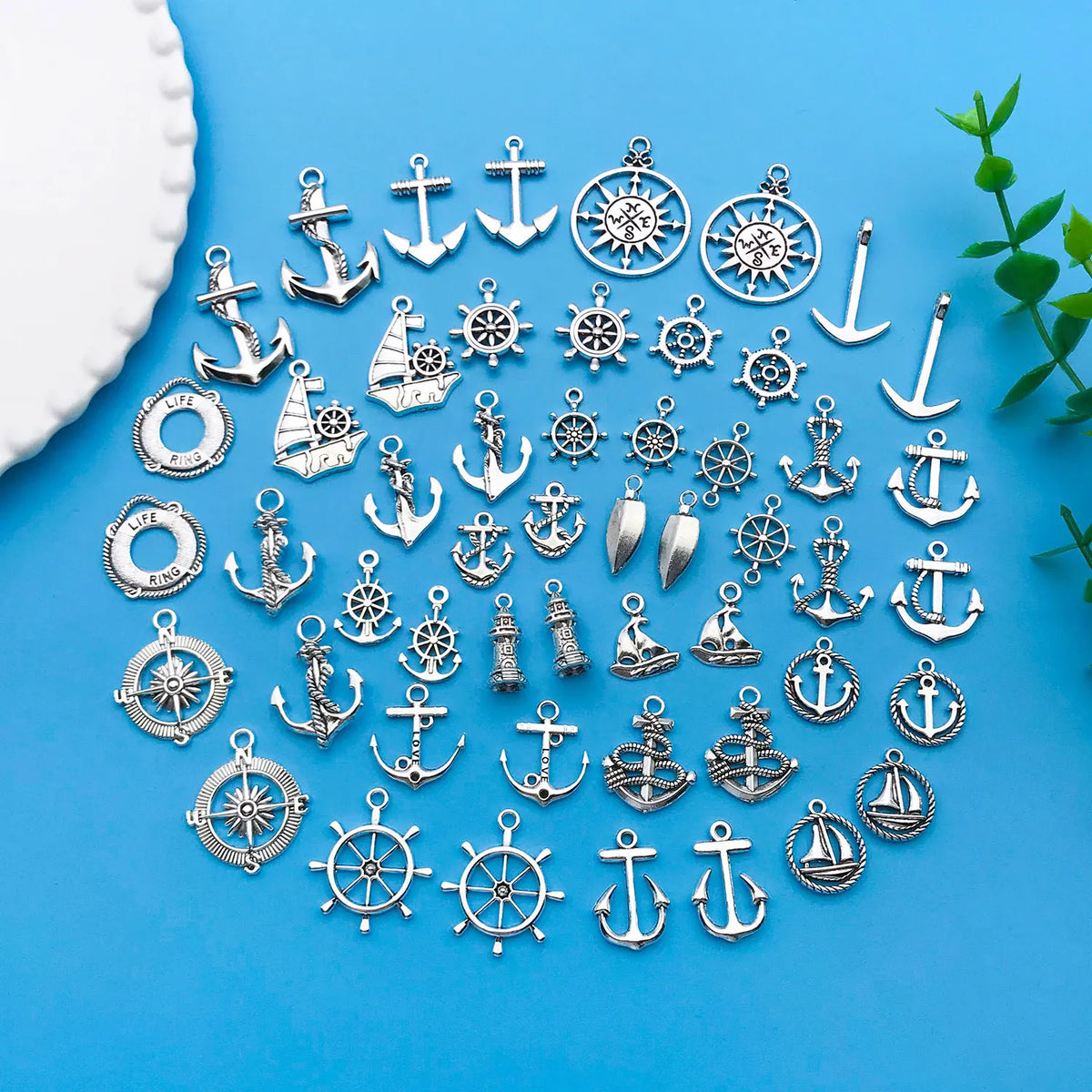A collection of vintage ship anchor charms and nautical jewelry components arranged on a blue surface.