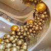 A close-up of a large arrangement of chrome metallic gold and bronze balloons hanging in a curved display.