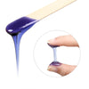 A wooden stick dipped in purple hard wax is shown dripping onto a finger for body hair removal.