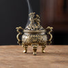 A vintage brass incense burner holder with a lion motif is shown on a wooden surface.