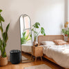 A full length arched wall mirror leaning against a wall in a bedroom setting.