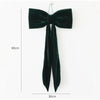 A dark green velvet bow shaped like a Christmas tree is displayed against a white background.