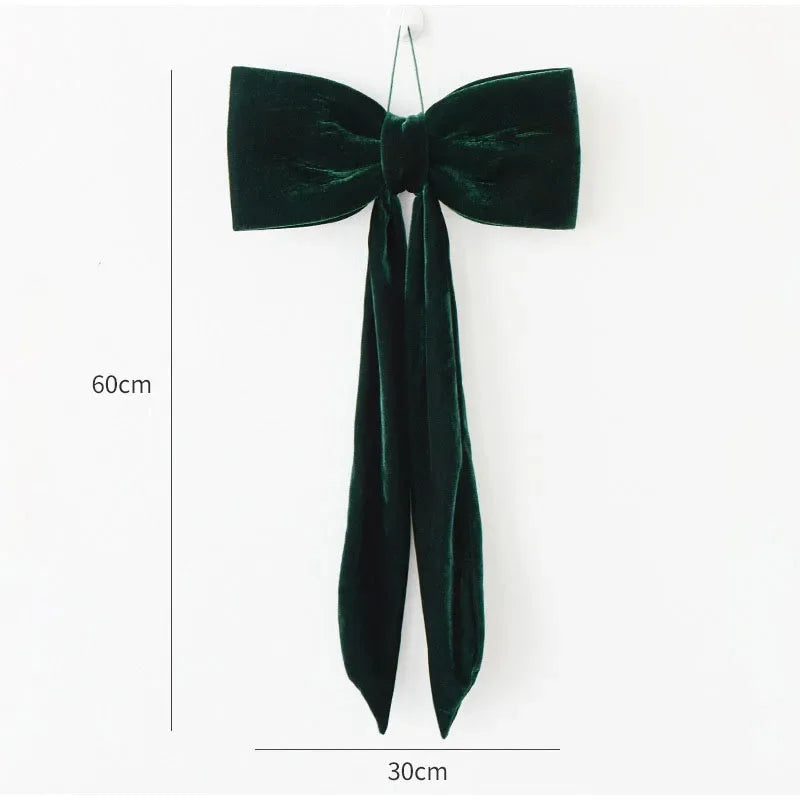 A dark green velvet bow shaped like a Christmas tree is displayed against a white background.