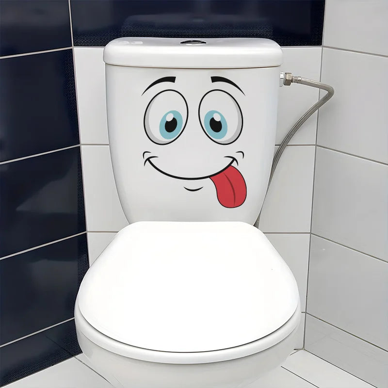 A white toilet decorated with a funny cartoon face and tongue, set against a tiled bathroom wall.