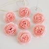 A collection of pink silk peony artificial flowers arranged on a white surface.