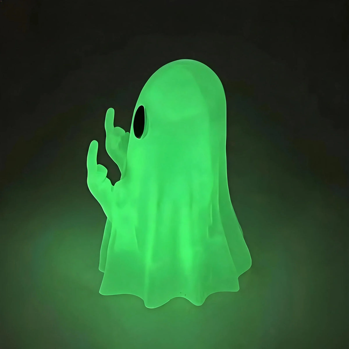 A glowing green ghost figurine with an open hand gesture, used as Halloween desk decor.