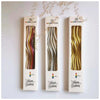 Three vertical candles with curved metallic designs for a birthday celebration
