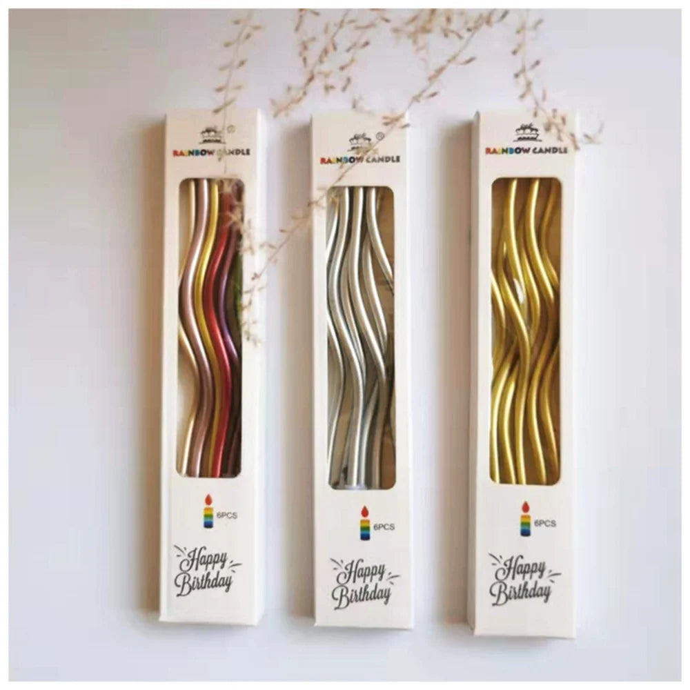 Three vertical candles with curved metallic designs for a birthday celebration