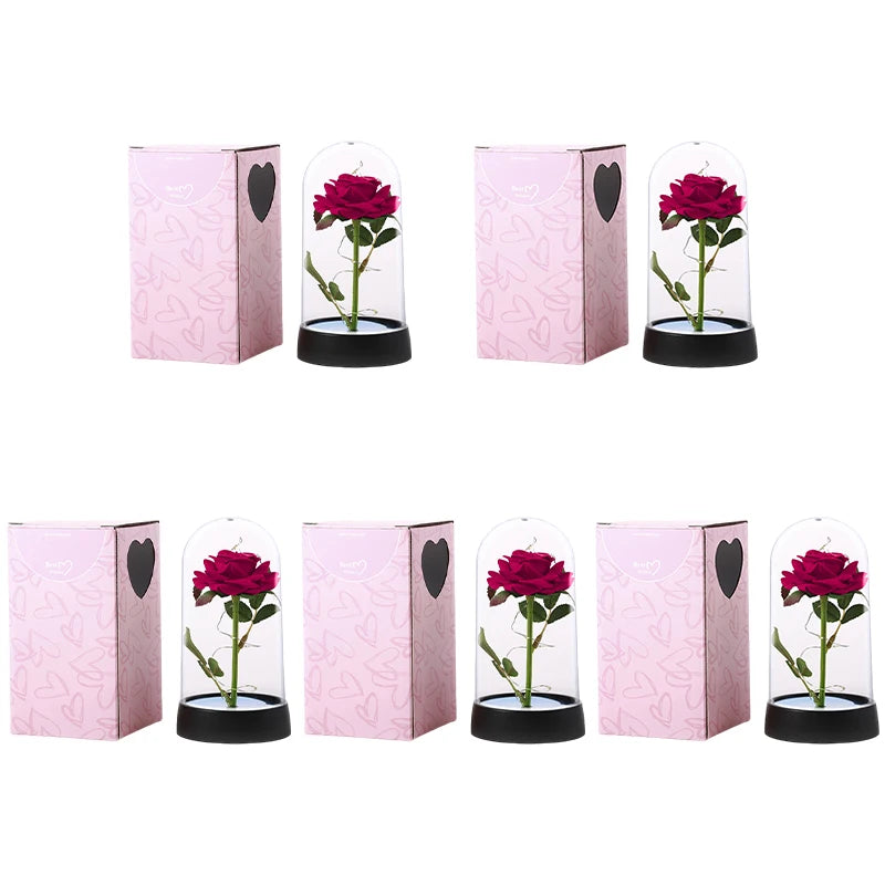 A set of five pink decorative flowers with red roses inside glass domes and black bases.