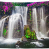 A panoramic photograph of a waterfall cascading down mossy rocks surrounded by lush green rainforest foliage.