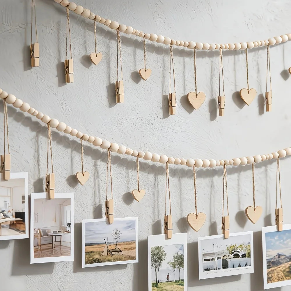 A beige beaded photo display garland featuring heart-shaped wooden clips hanging against a white wall.