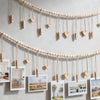 A beige beaded photo display garland featuring heart-shaped wooden clips hanging against a white wall.