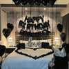 A bedroom decorated for a birthday party with black balloons and foil letters spelling 'HAPPY BIRTHDAY LOVE' above a bed.