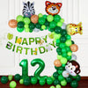A green balloon garland arch decorated with safari animals like a tiger and zebra for a birthday celebration.