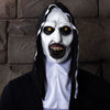 A person wearing a realistic horror nun latex mask with pale white face, dark eyes, and long black hair against a stone wall.