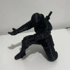 A black 3D ninja figure is shown in a dynamic pose, standing on a white surface.