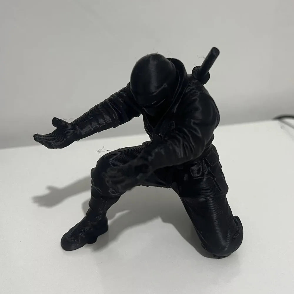 A black 3D ninja figure is shown in a dynamic pose, standing on a white surface.