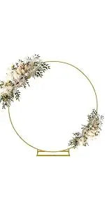 A gold-rimmed circular frame decorated with white floral greenery, suitable for displaying vintage bud glass vases.