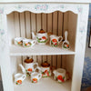 A collection of handcrafted miniature mushroom tableware for dollhouses displayed on a white shelf.