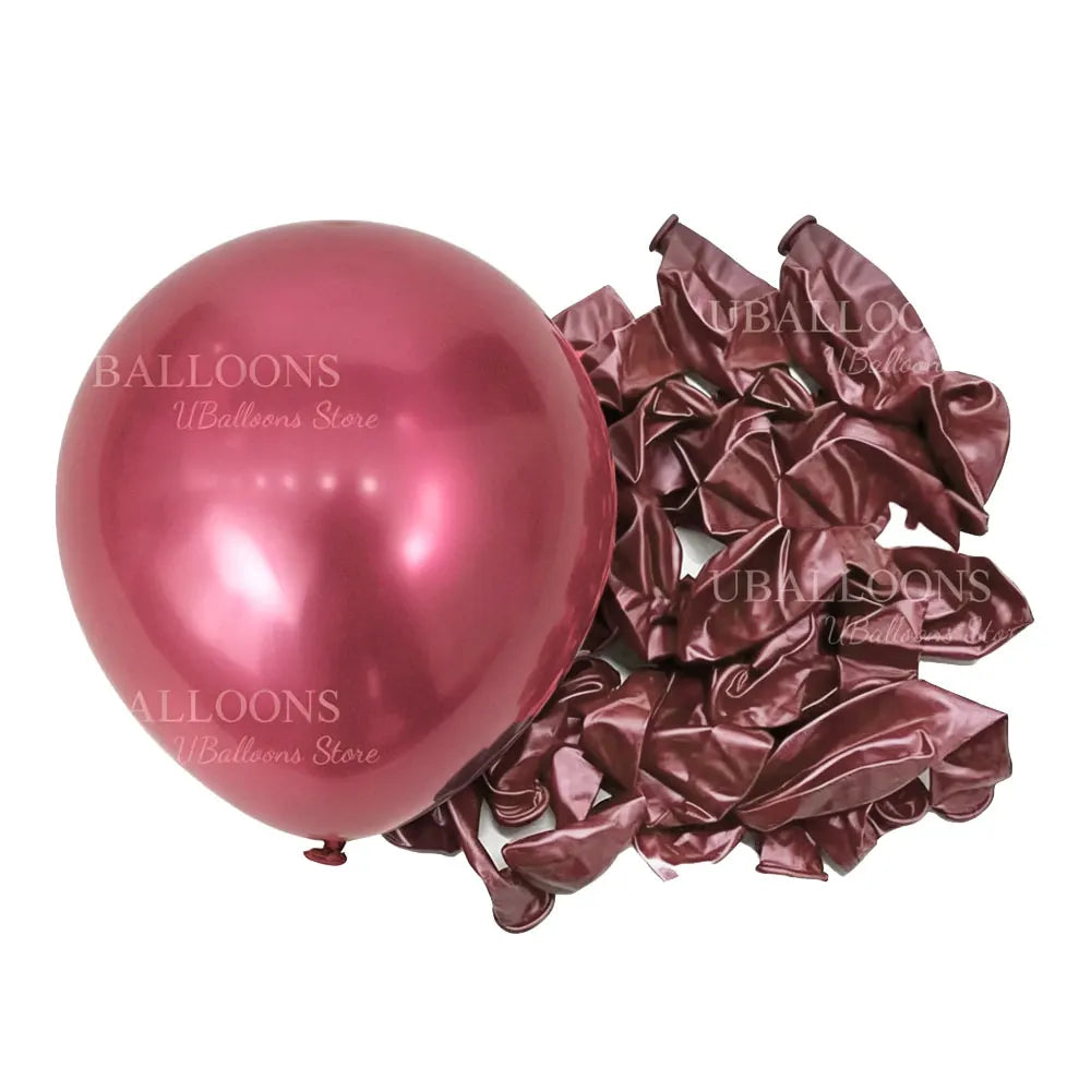 A glossy pink balloon next to a pile of deep burgundy latex balloons for parties and events.