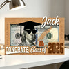 A wooden sign featuring a portrait of Jack surrounded by US currency and the text Congrats Class of 2026