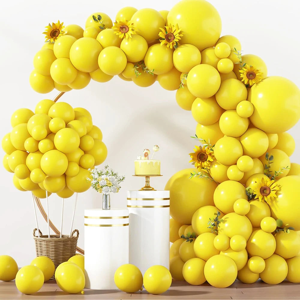 A large archway made of yellow latex balloons decorated with sunflowers and citrus fruits.